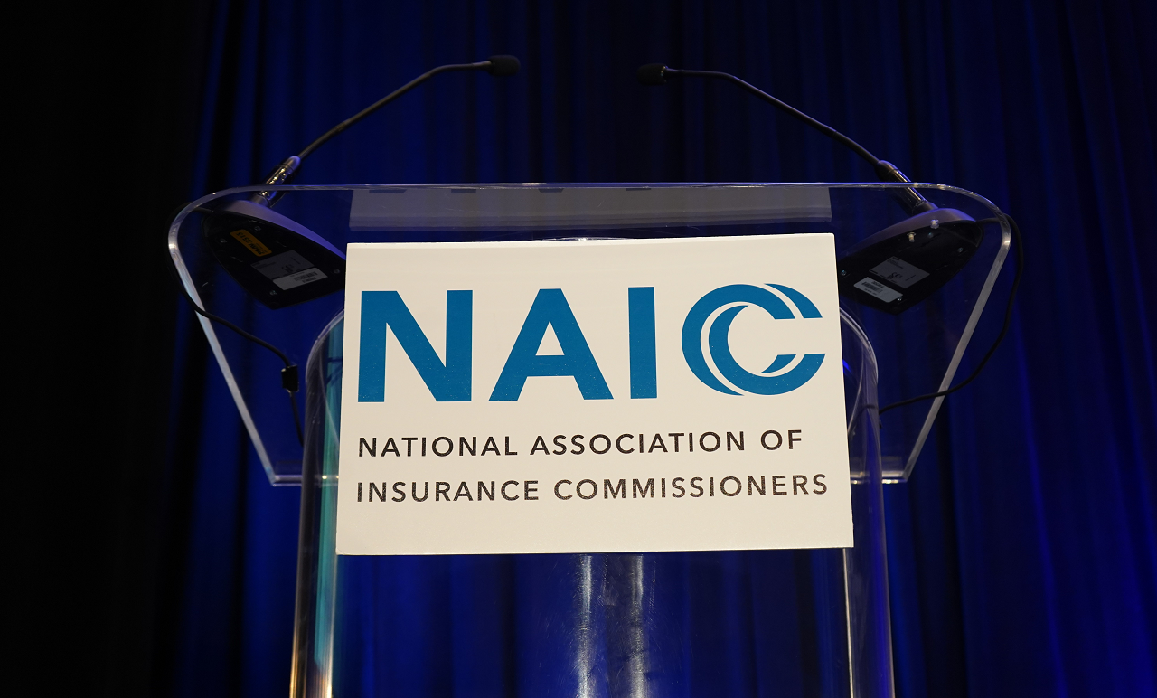 White Sign with Blue NAIC Logo from Podium at the 2023 NAIC International Insurance Forum