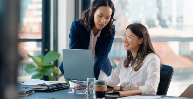 People in business setting looking at a computer and chatting